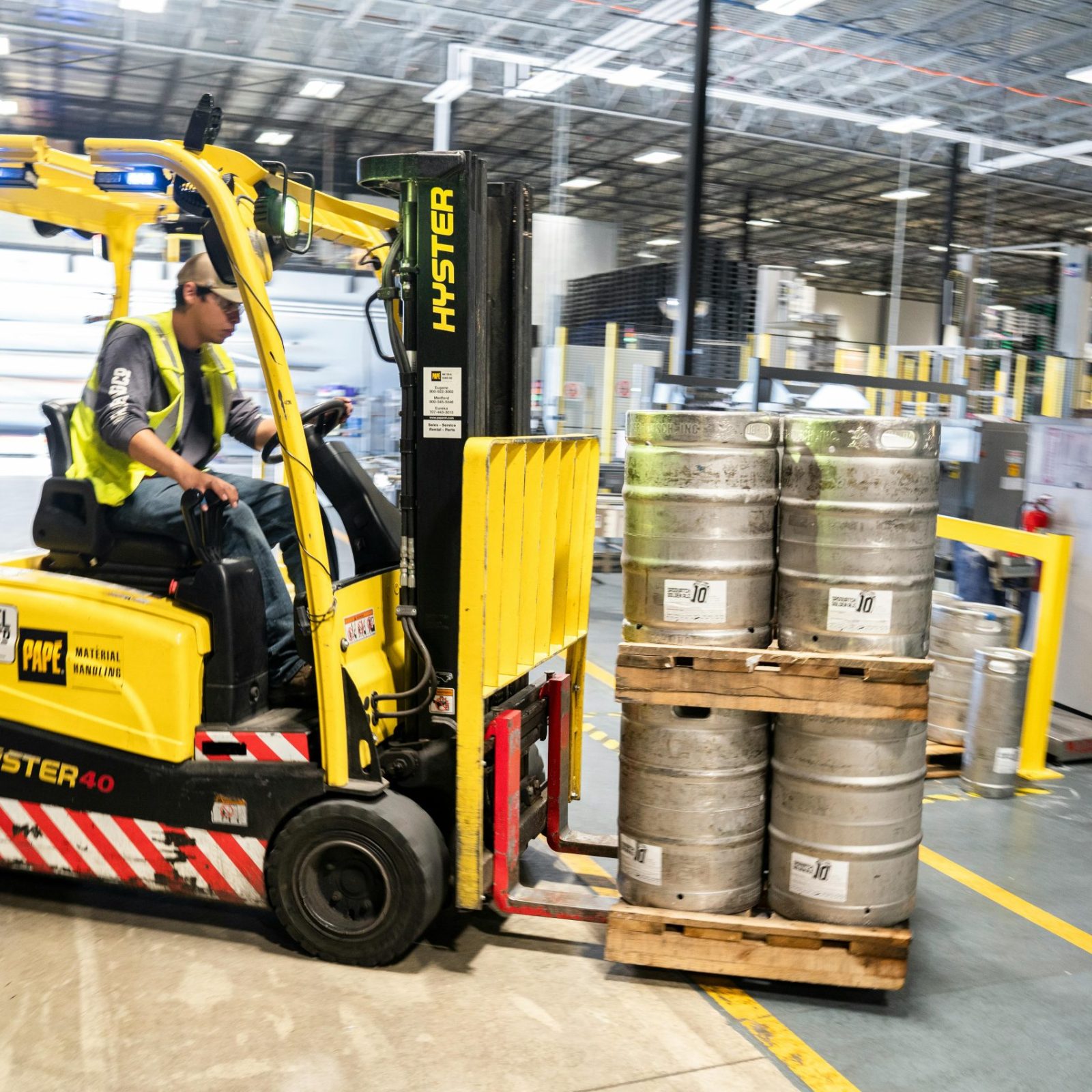 pexels-photo-1267337-1267337 Forklift operator in warehouse moving beer kegs for distribution.