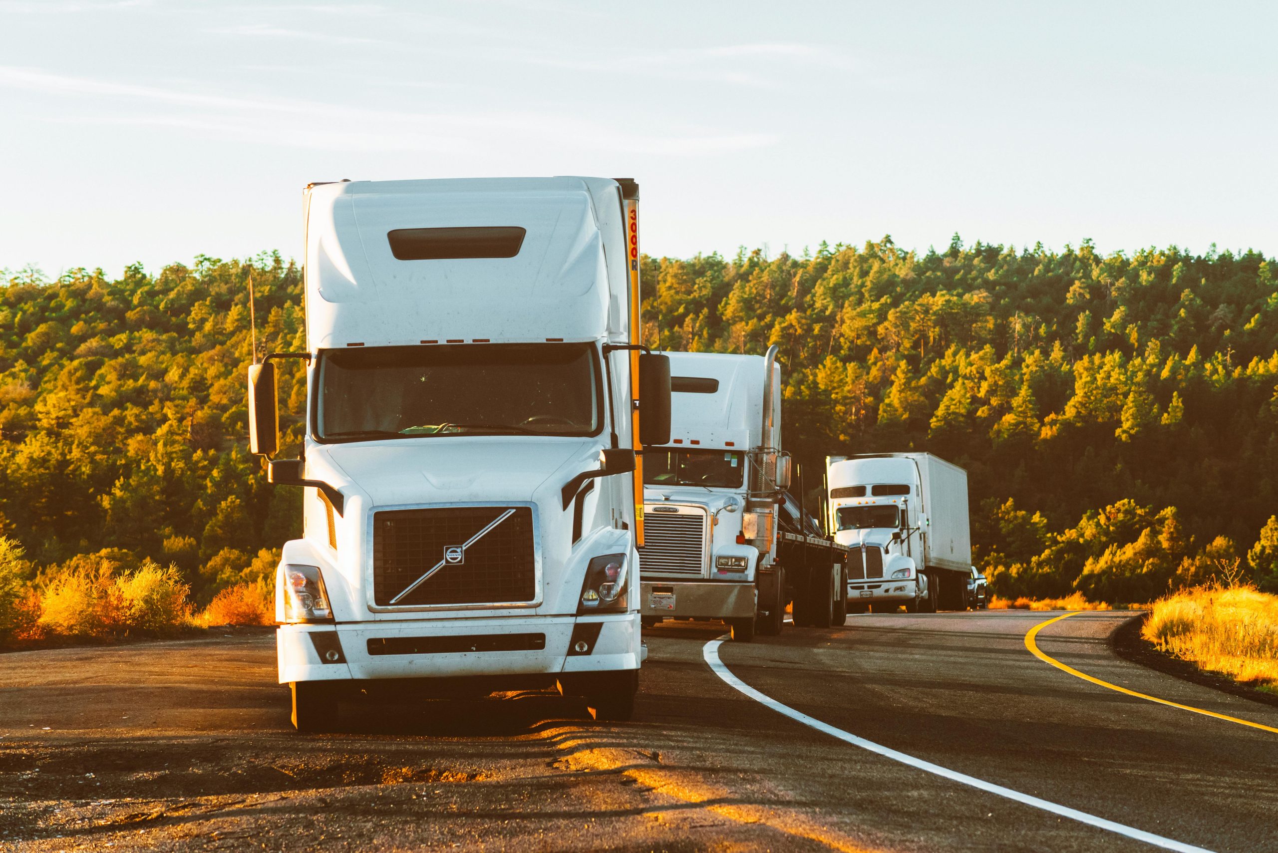 pexels-photo-2199293-2199293-1 Three semi trucks driving on a highway through a forested landscape in Arizona.