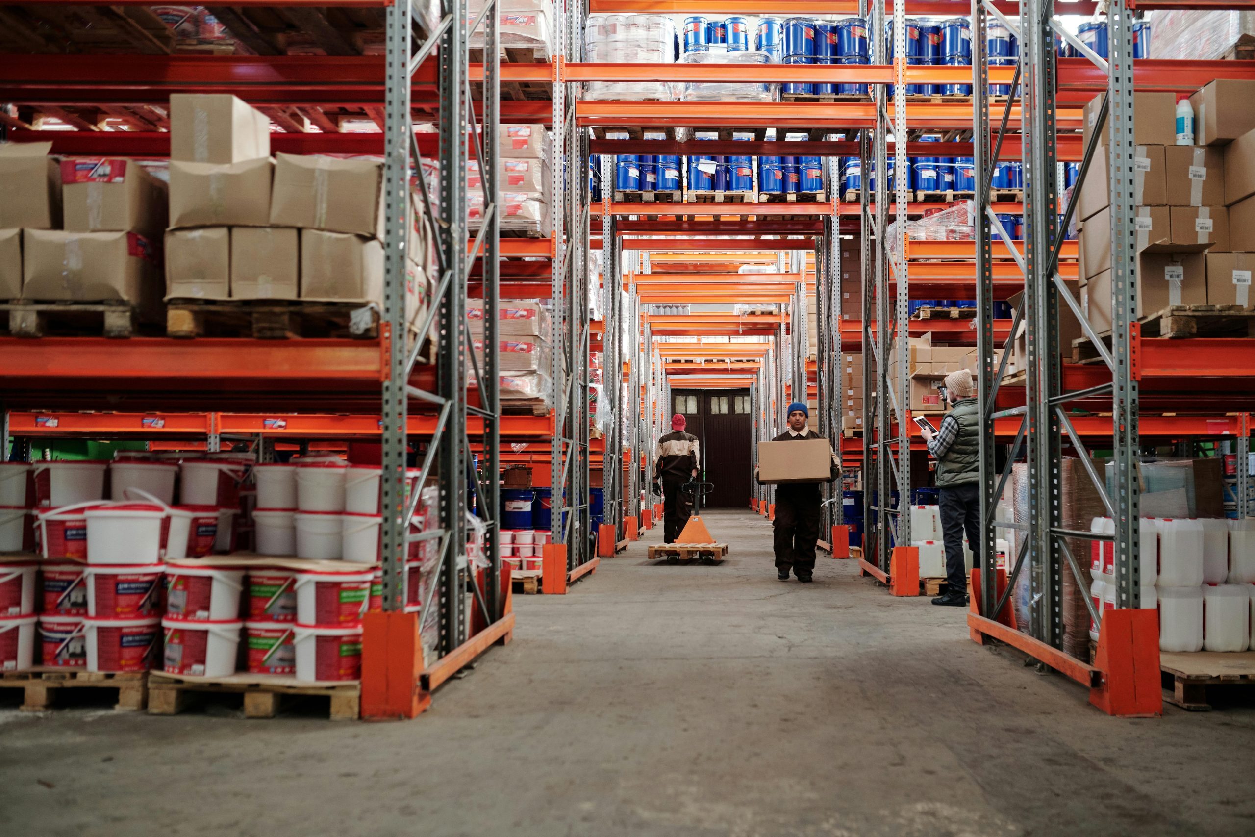 pexels-photo-4483862-4483862 Warehouse interior showing workers handling boxes and organized shelves filled with products.